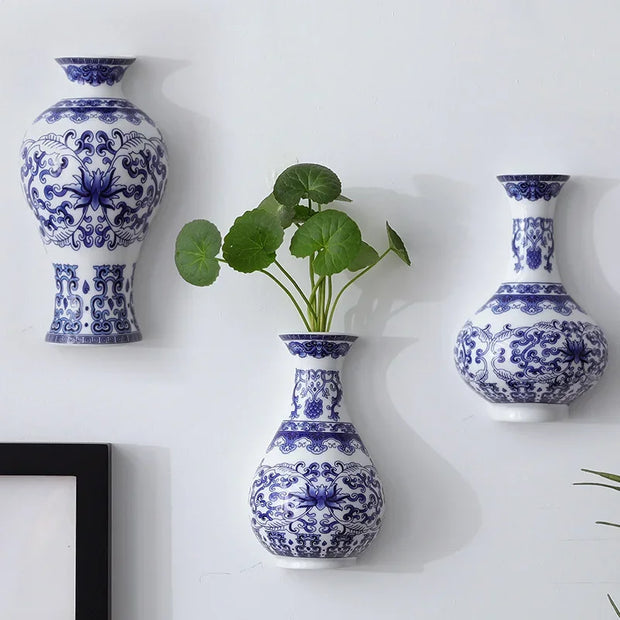 Blue and white patterned vases on a white wall with a plant in the center.