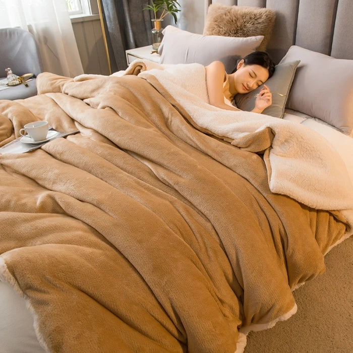 Woman sleeping under a fluffy beige blanket on a bed with a cup and saucer on a nightstand.