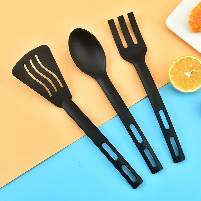 Set of black kitchen utensils including a spatula, spoon, and fork on a colorful background.