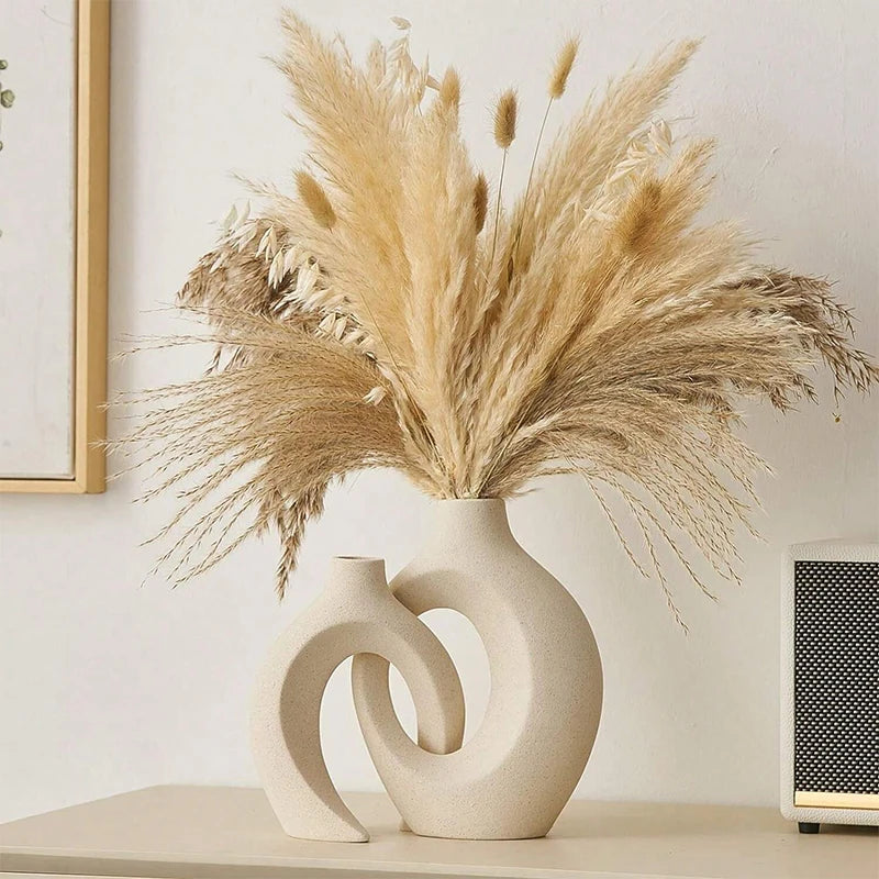 Decorative vase with pampas grass on a shelf against a light wall.