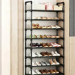 Black shoe rack with multiple pairs of shoes on shelves against a neutral wall.