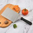 Knife on a wooden cutting board with vegetables on a marble surface
