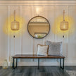 Modern interior with a round mirror, wooden bench, and decorative pillows.