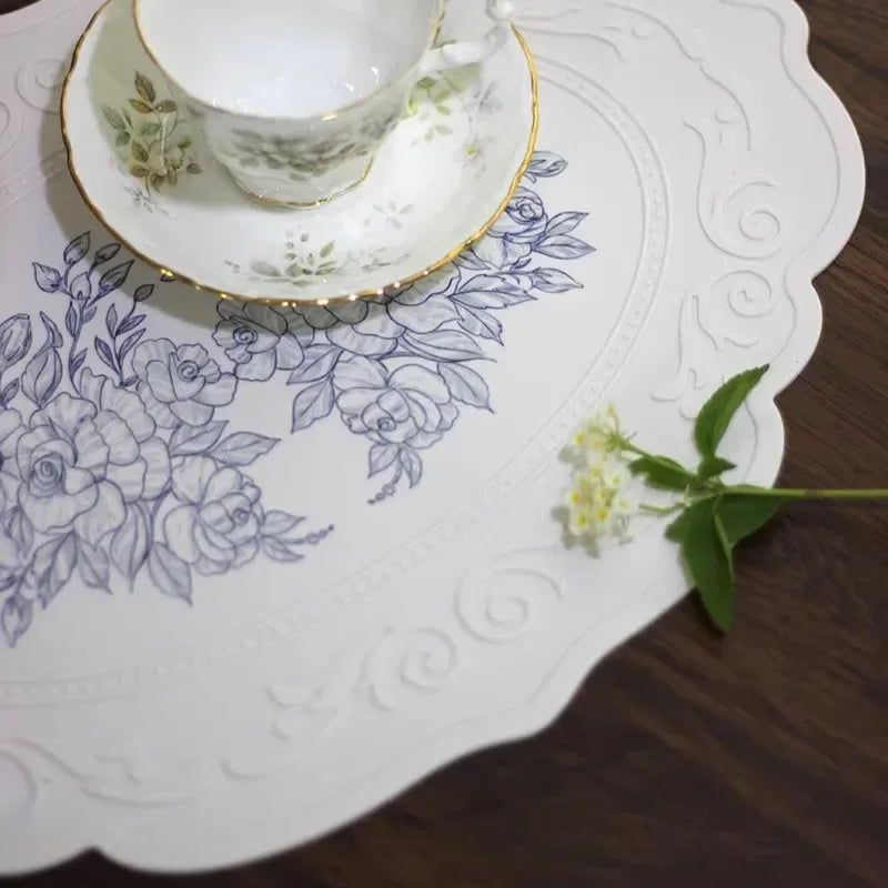Teacup and saucer on a decorative tablecloth with floral pattern