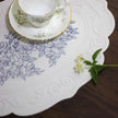 Teacup and saucer on a decorative tablecloth with floral pattern