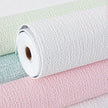 Three rolls of textured wallpaper in green, white, and pink.