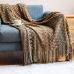 Patterned blanket draped over a blue armchair with a cup on a saucer.