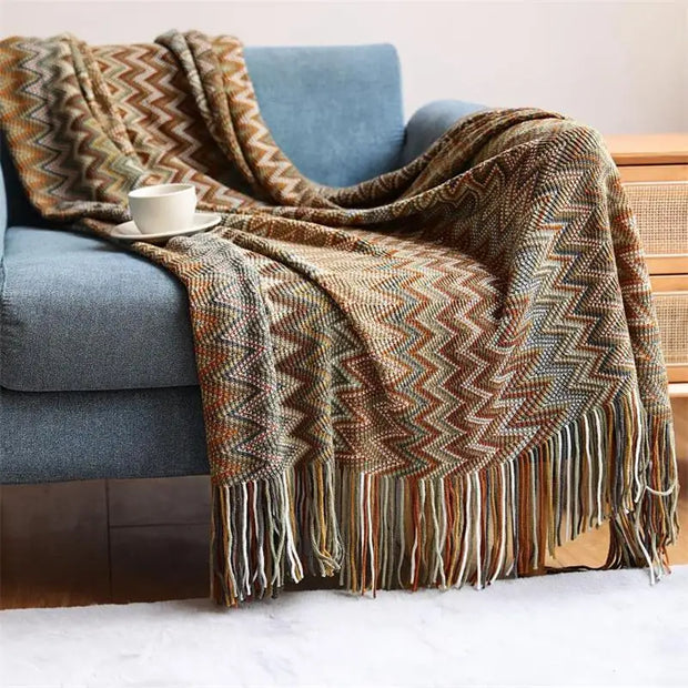 Patterned blanket draped over a blue armchair with a cup on a saucer.