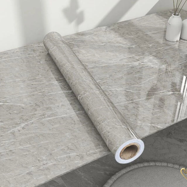 Roll of gray marble-patterned vinyl wrap on a table