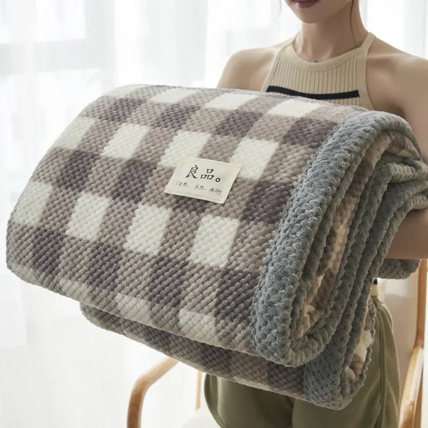 Person holding a checkered blanket with a visible brand label against a white curtain background