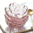 Pink glass bowl with gold rim on a white surface with a gold spoon.