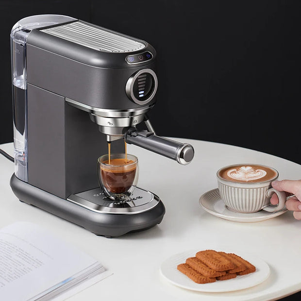Espresso machine making a shot of espresso on a white surface with a cup of coffee and cookies.
