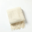 White textured throw blanket with fringe on a white background