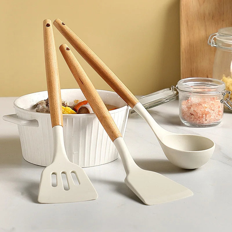 Set of kitchen utensils including a spatula and ladle on a countertop with a neutral background.