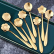 Set of gold floral spoons on a green tray with a dark textured background