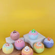 Colorful bath bombs with small figures on a yellow background