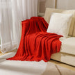 Red blanket draped over a white sofa in a living room setting.
