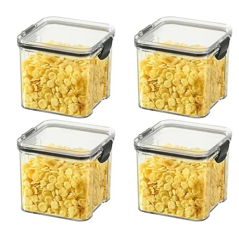 Four square storage containers with lids filled with yellow cereal on a white background