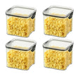 Four square storage containers with lids filled with yellow cereal on a white background