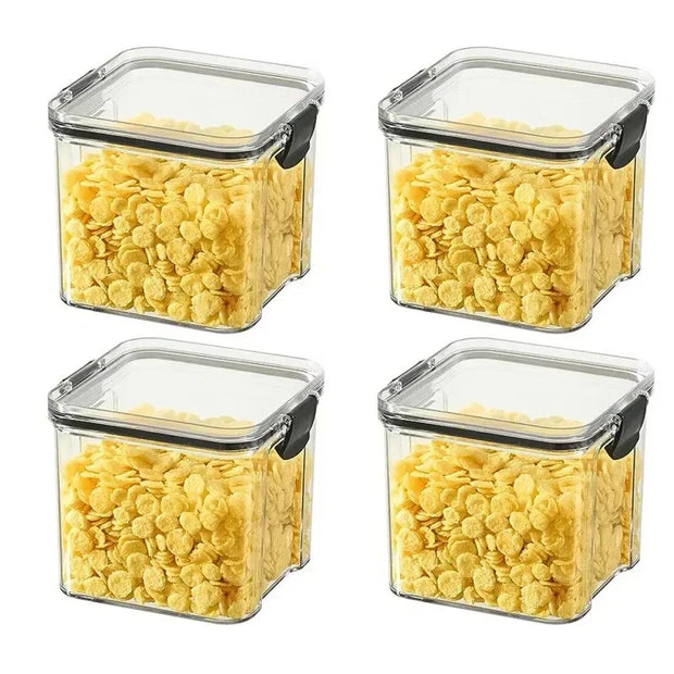 Four square storage containers with lids filled with yellow cereal on a white background