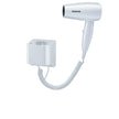 White hair dryer with coiled cord attached to a wall socket on a white background