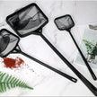 Three black butterfly nets on a marble surface with plants and seeds.