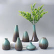 Set of ceramic vases with gradient finish and greenery on a neutral background