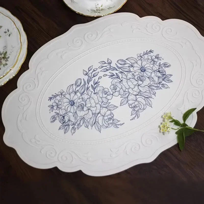 Decorative white placemat with floral design on a wooden surface