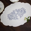 Decorative white placemat with floral design on a wooden surface