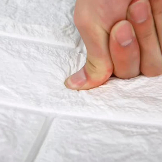 Close-up of a hand pressing into a white textured surface