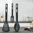 Set of black kitchen utensils including a spatula, fork, and spoon on a kitchen counter.