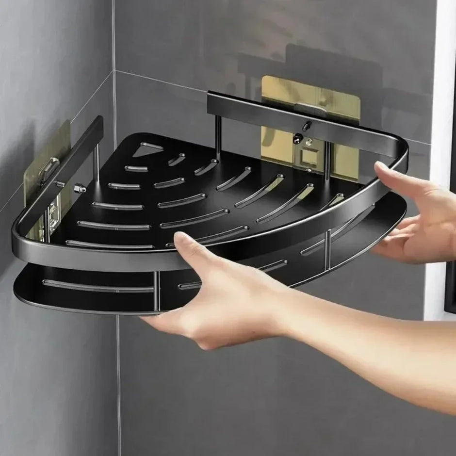 Black corner shower caddy being held against a gray tiled wall