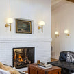 Living room with white brick fireplace, black sofa, and wall sconces.