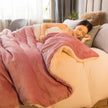 Woman lying on a couch under a pink blanket in a cozy living room.