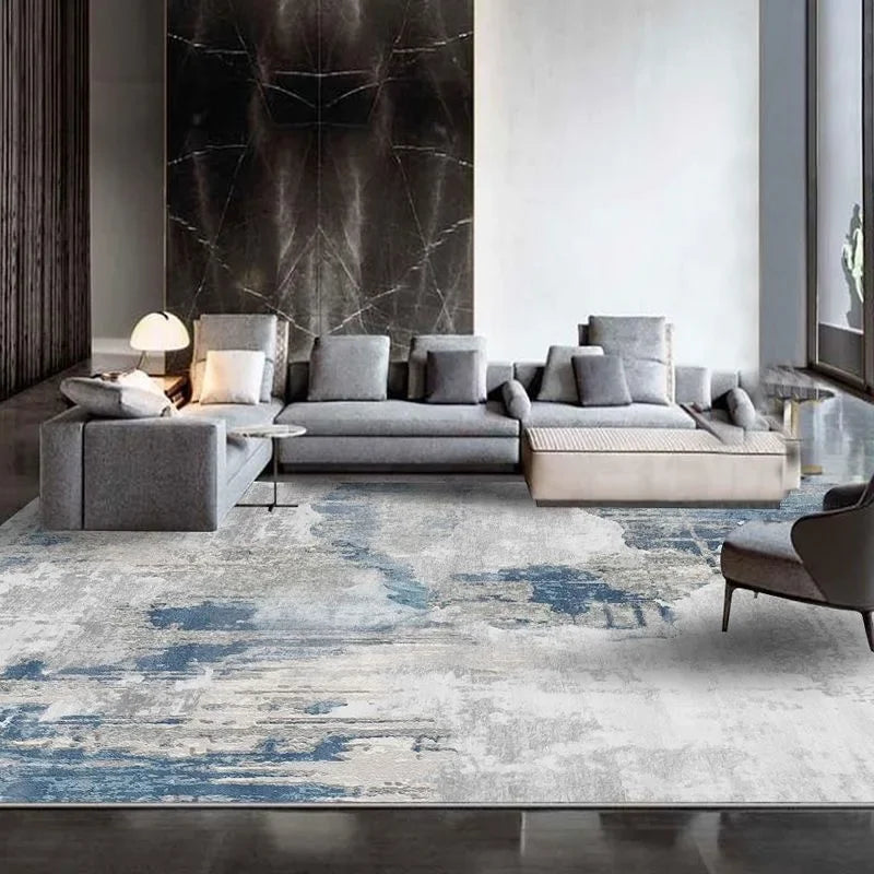Modern living room with a gray sectional sofa and abstract patterned rug.