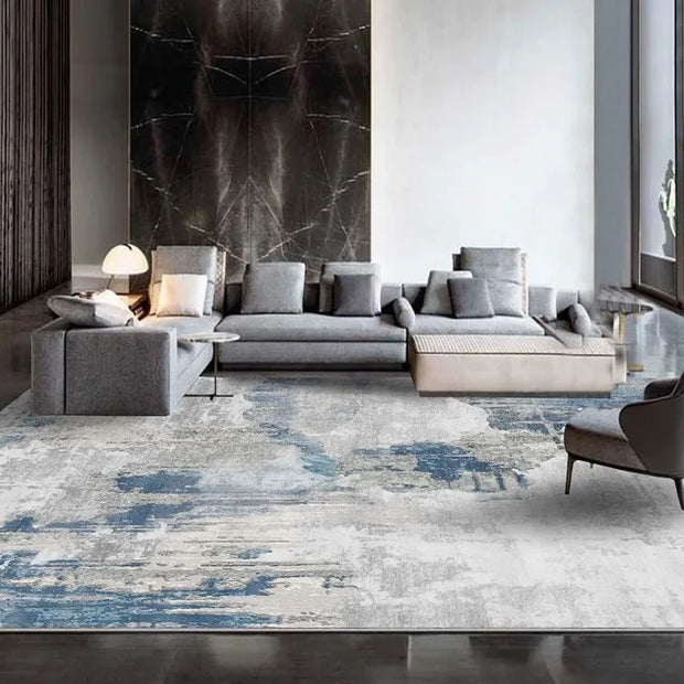 Modern living room with a gray sectional sofa and abstract patterned rug.