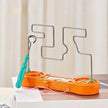 Metal wire frame with orange base and blue handle on a light background