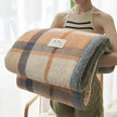 Person holding a checkered blanket with a visible brand label against a light background