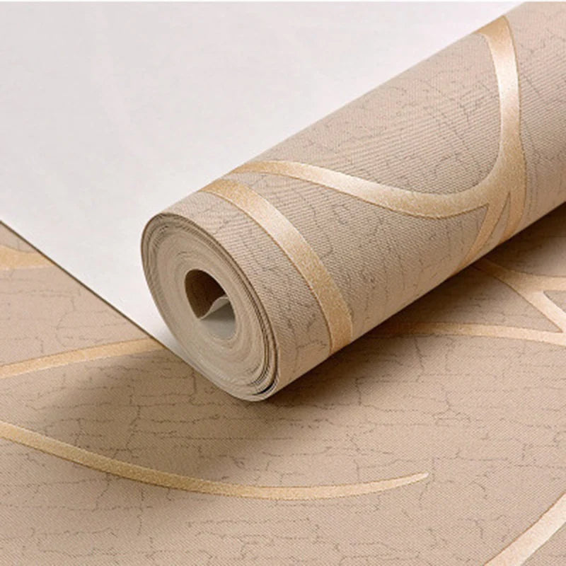 Roll of beige wallpaper with gold accents on a matching surface.