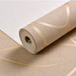 Roll of beige wallpaper with gold accents on a matching surface.