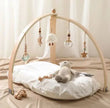 Wooden baby gym with hanging toys on a bed