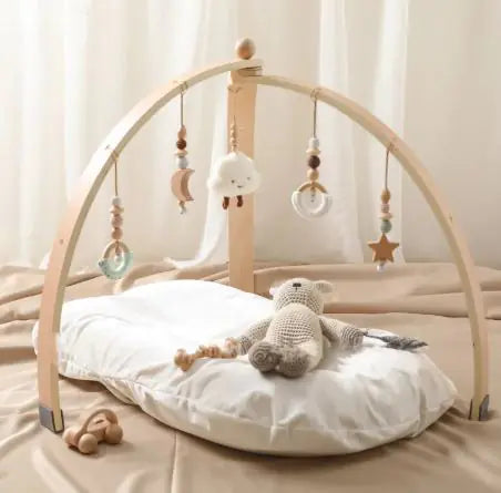 Wooden baby gym with hanging toys on a bed